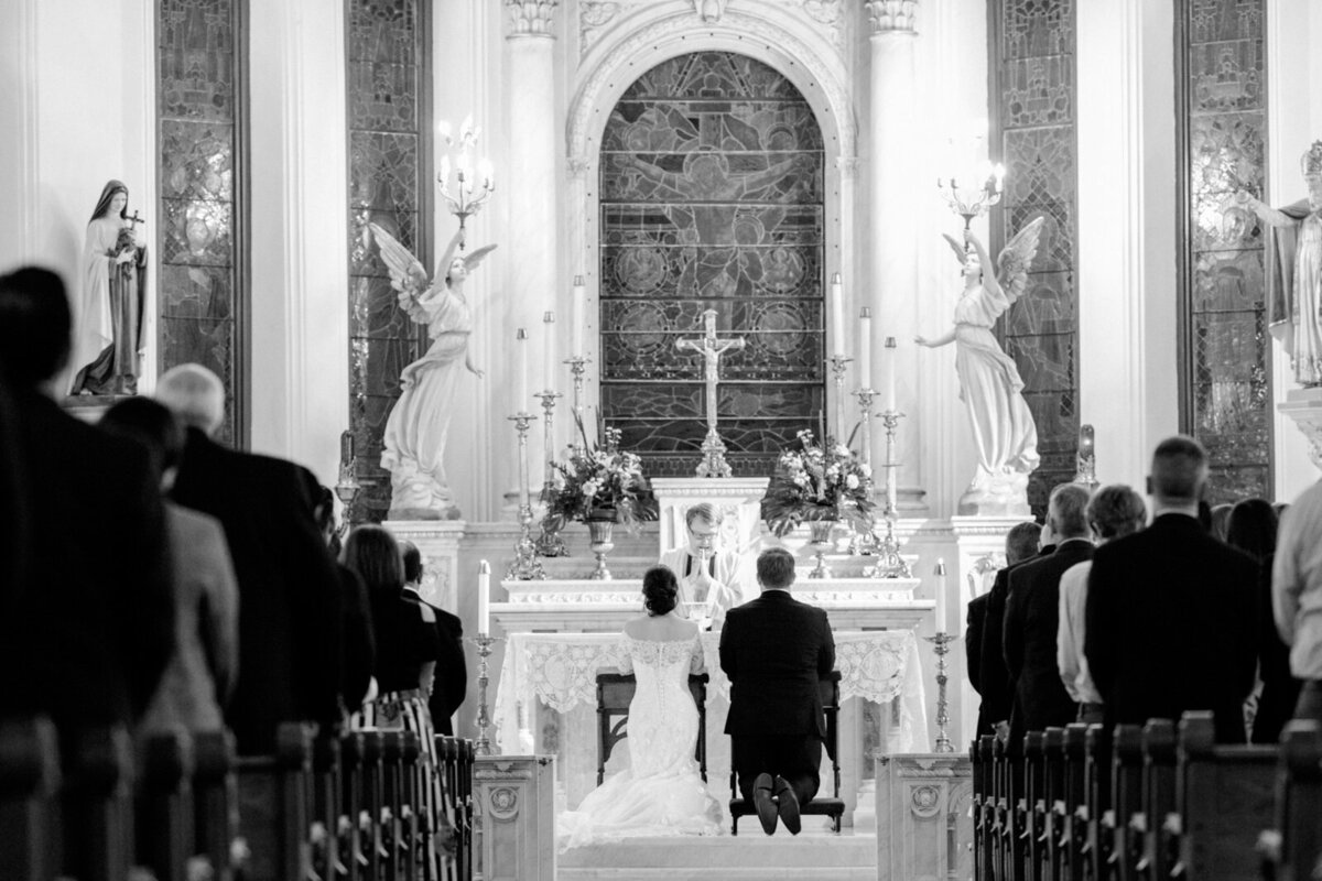 Wedding ceremony at Saint Patrick Cathedral in Fort Worth with the bride and groom kneeling at the altar.