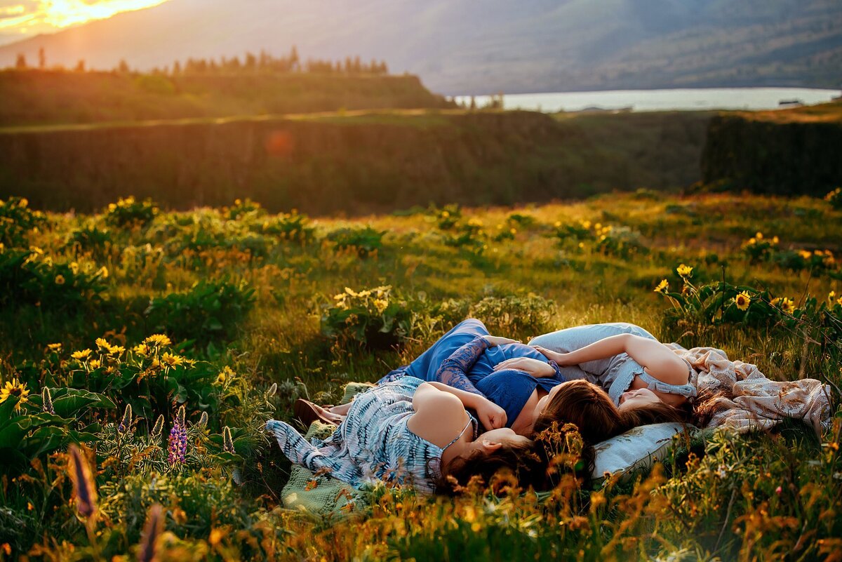 Mother and two daughters laying in a field of wildflowers at sunset