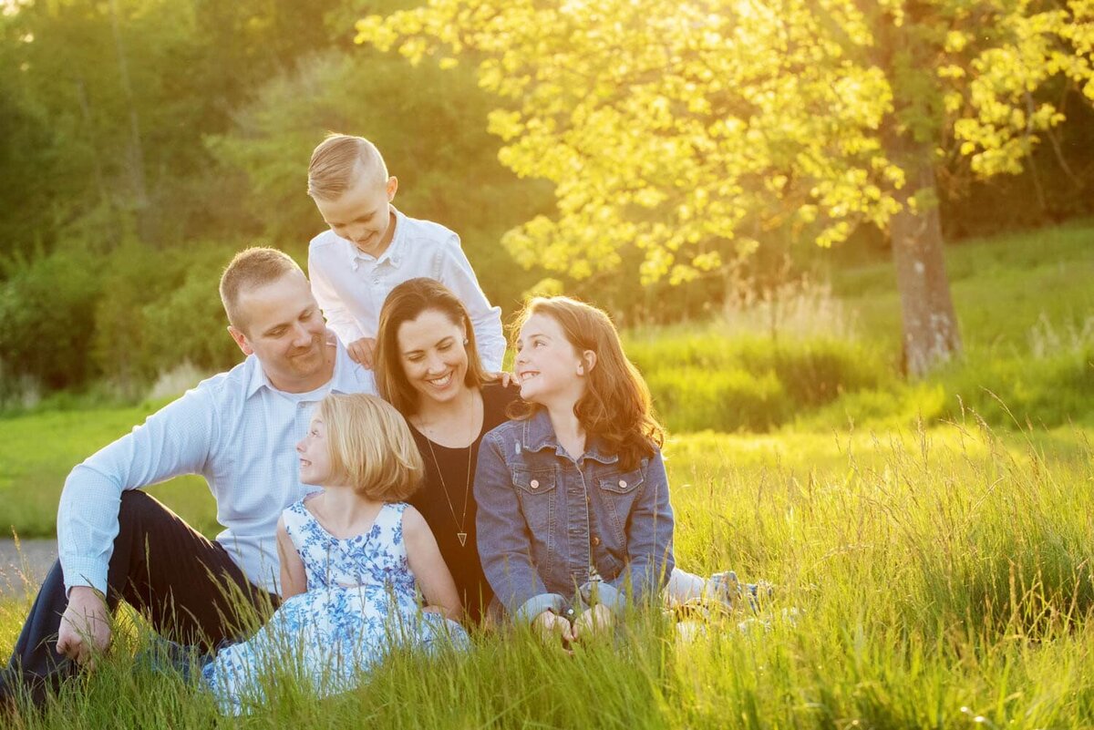 Dad and Mom, with two daughters and one sun, sit together at sunset at Deer Creek.