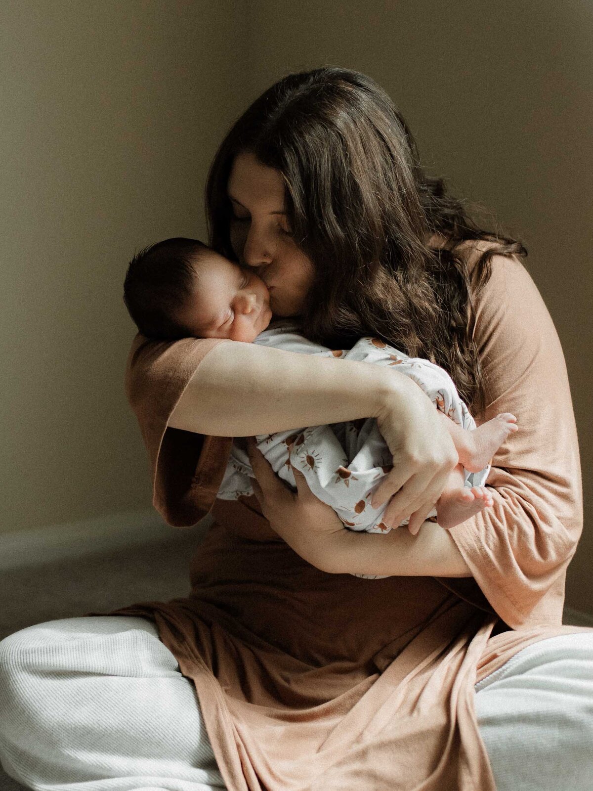 Mother kissing her baby during an in-home newborn photography session in Temecula.