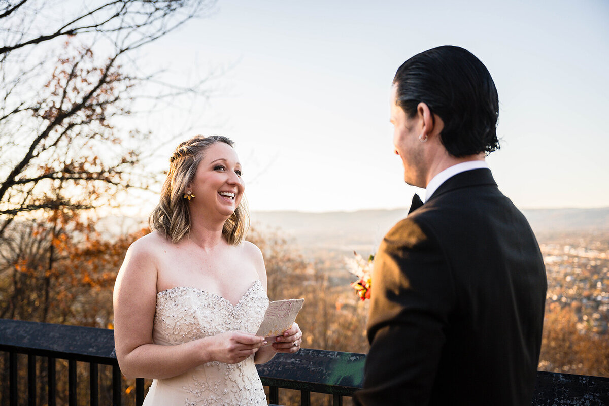 A marrier looks up from her vows and smiles at her partner during their ceremony at the Mill Mountain Star overlook in Roanoke, Virginia.