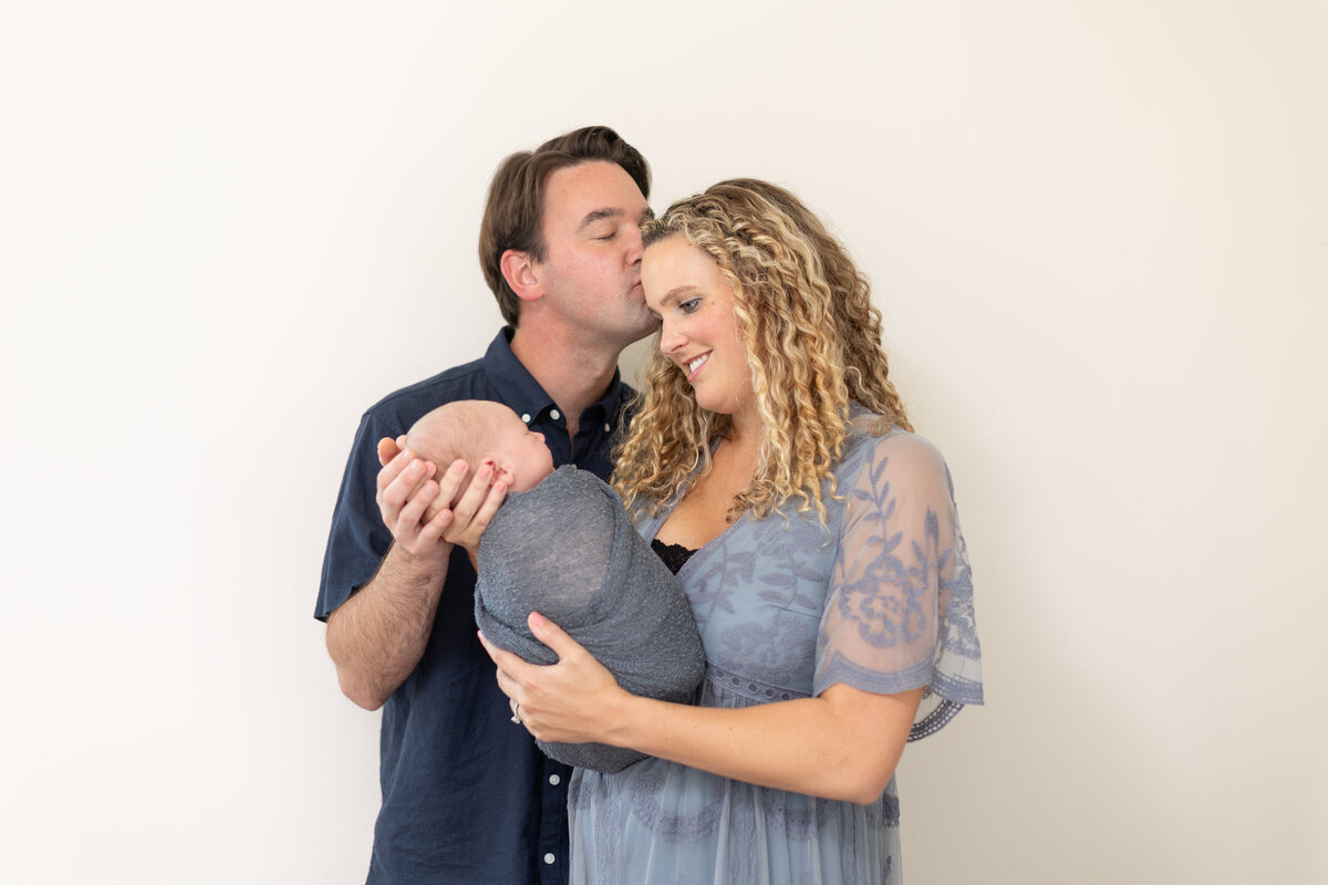 Couple kissing holding a newborn in long beach