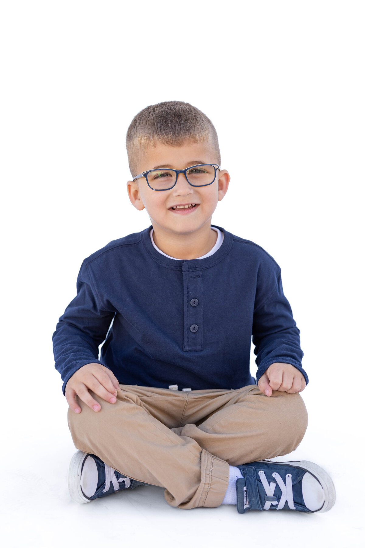 Preschool photo of little boy sitting crosslegged on the ground