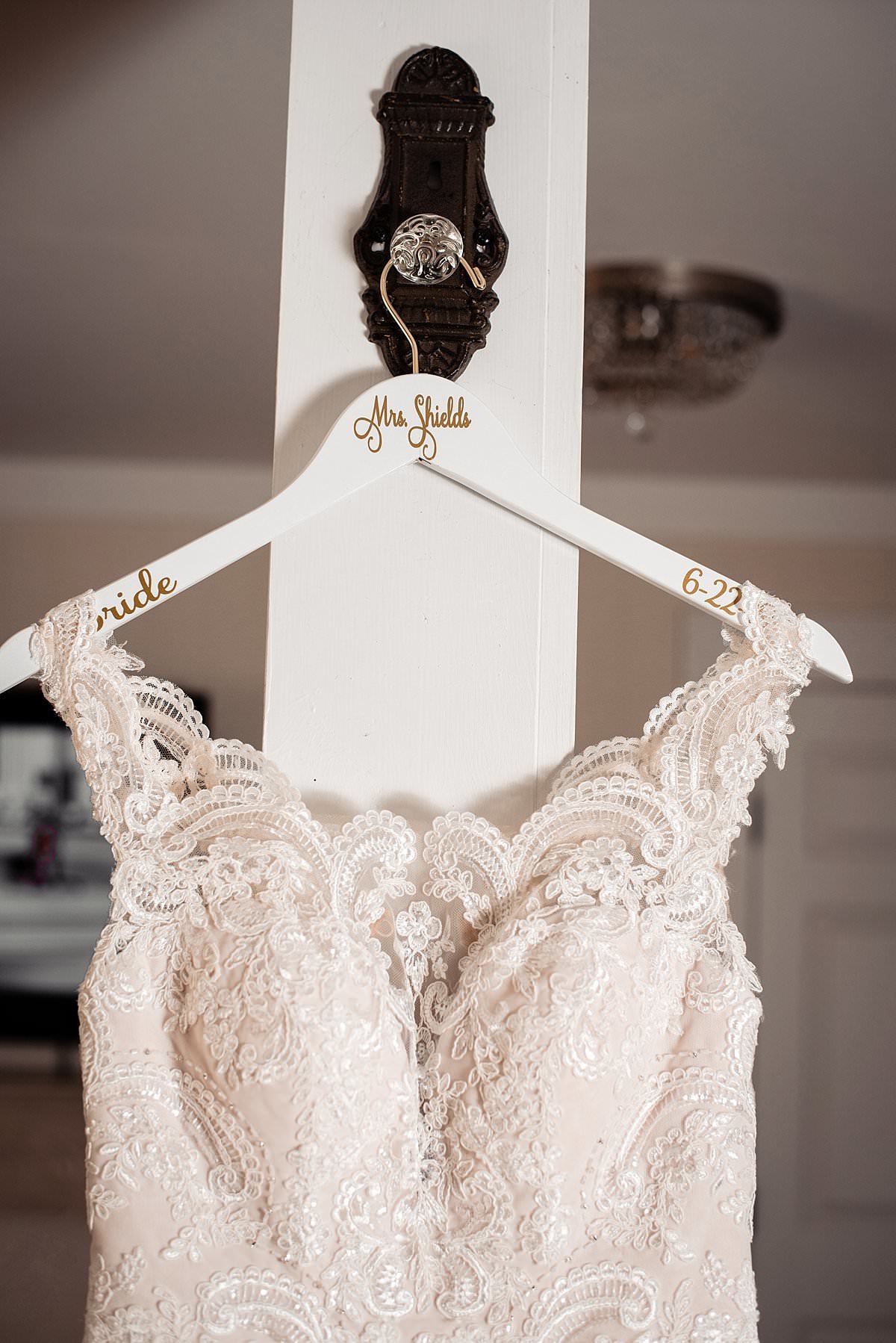 Brides wedding dress hanging on a custom white hanger with calligraphy