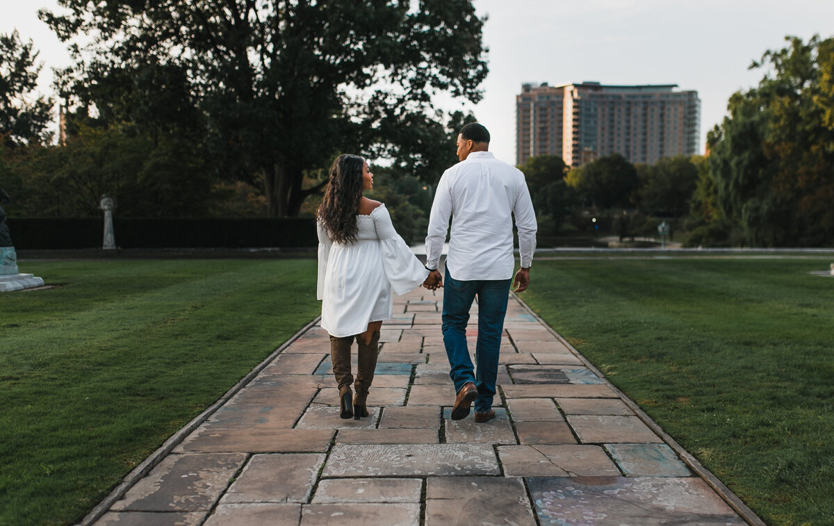 Woman and man hold hands and walk outside.