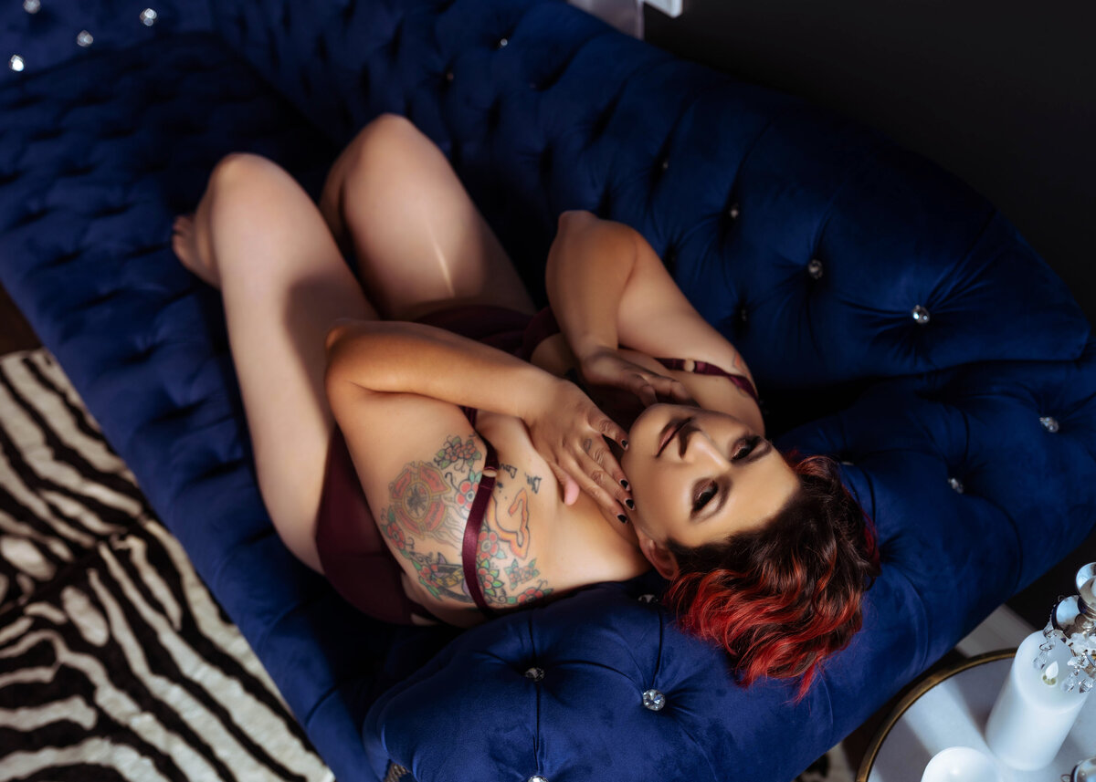 woman with tattoos in lingerie laying on blue couch