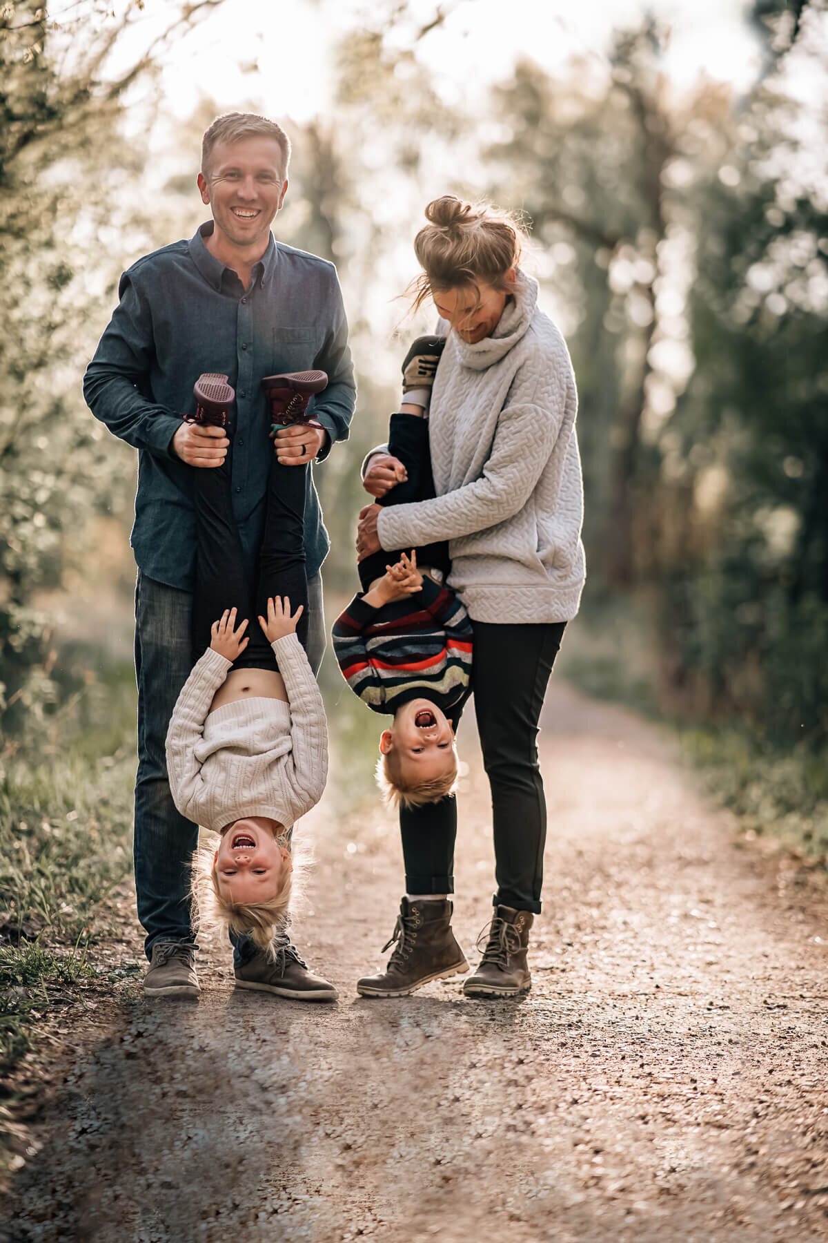 A mom and a dad hold their young kids upside down during an on location family photoshoot with Kate Simpson Photography.