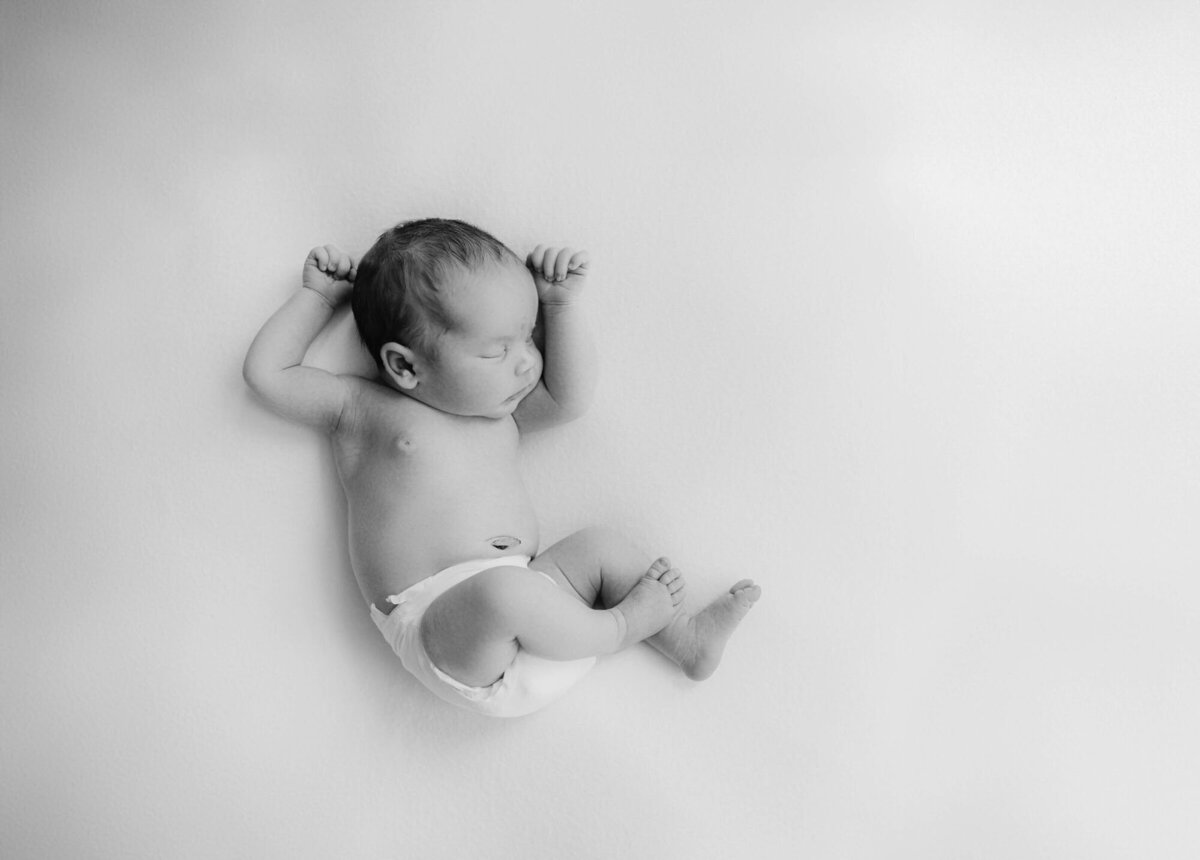Soft natural light portrait by a newborn photographer Bay Area, baby sleeping on bed.