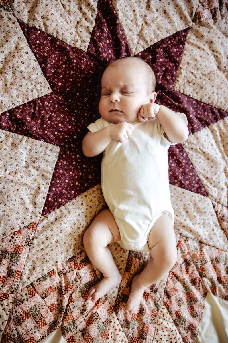 a newborn baby girl fast asleep on a handmade quilt