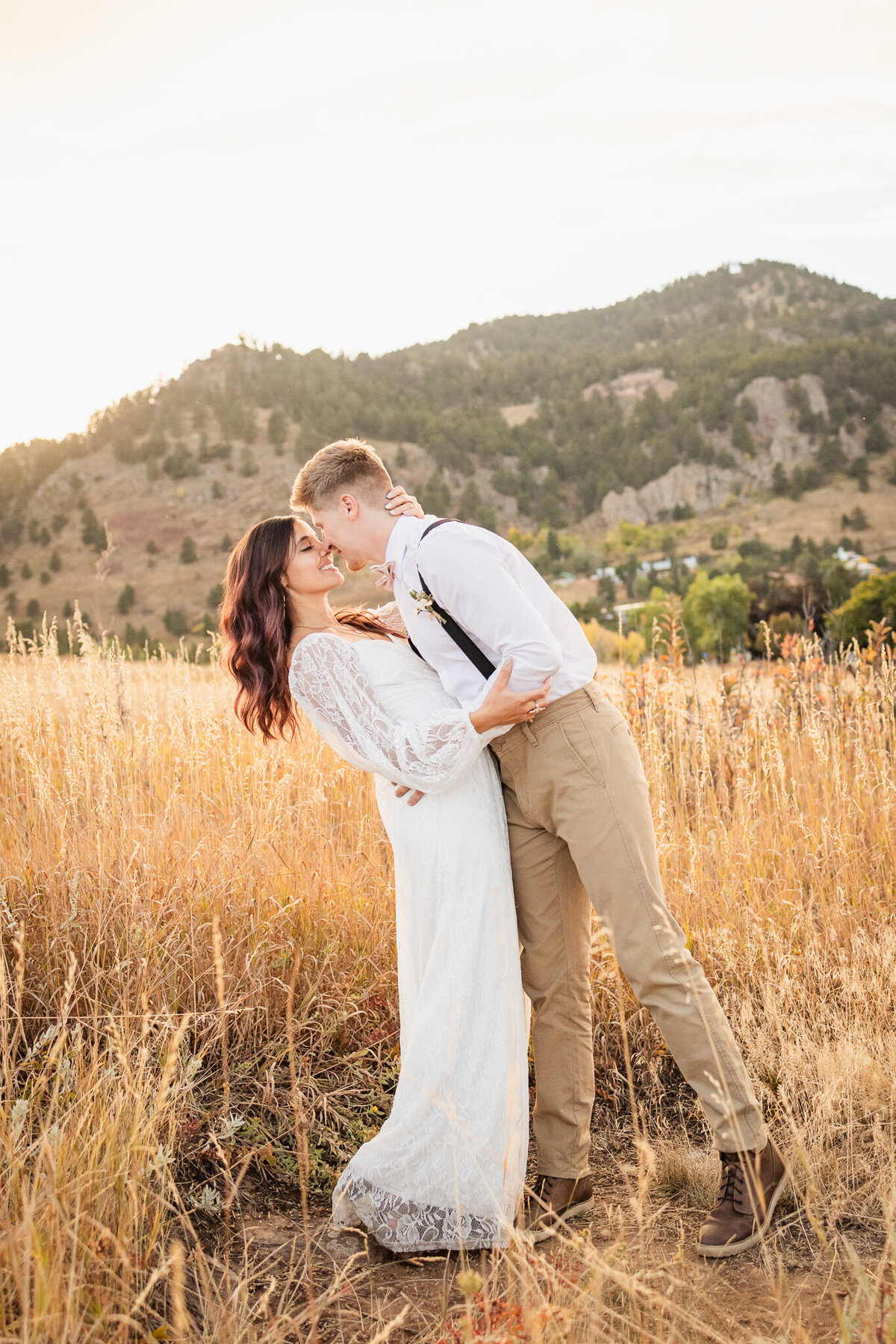 Bride and groom kiss in a field with mountains