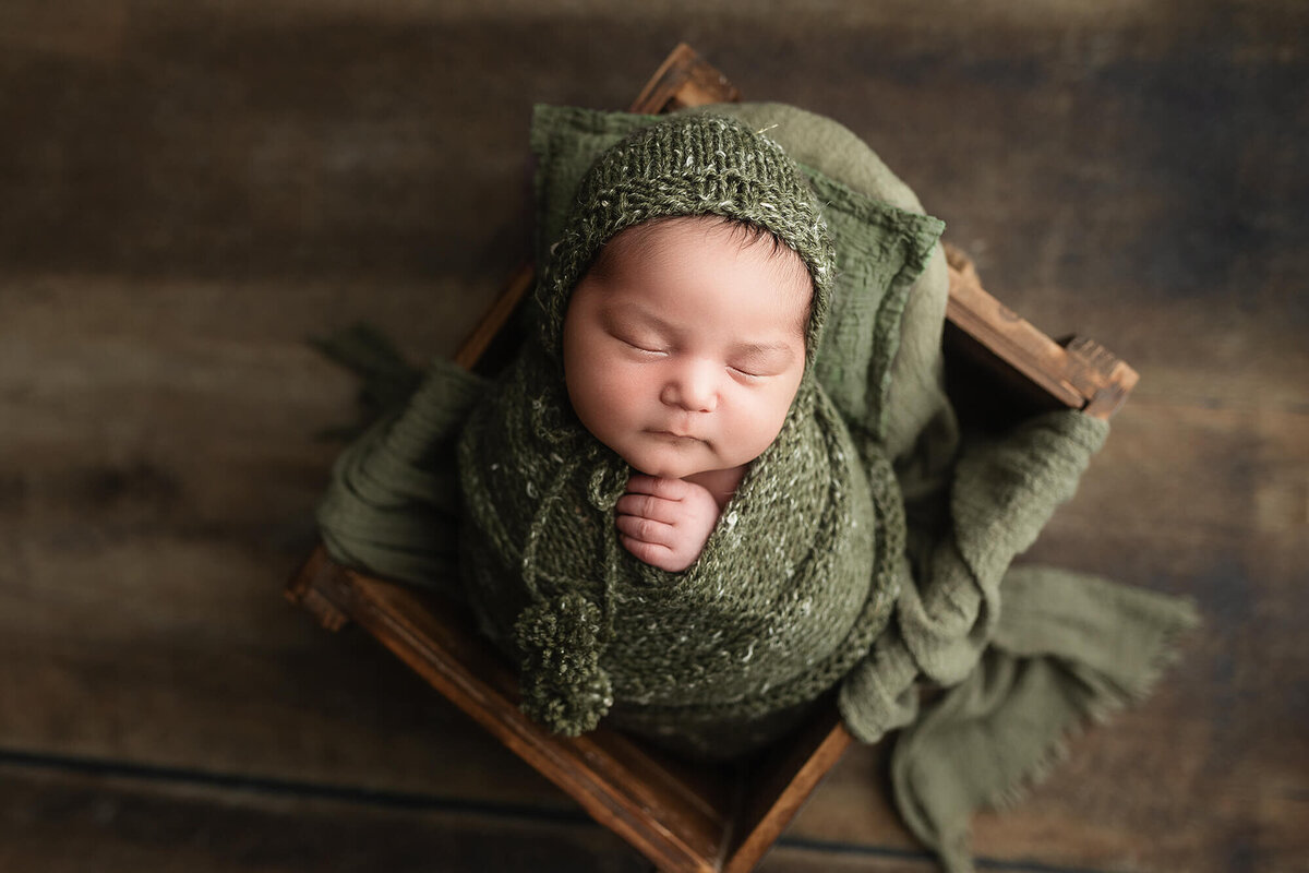 Baby boy wrapped in green during his newborn session.
