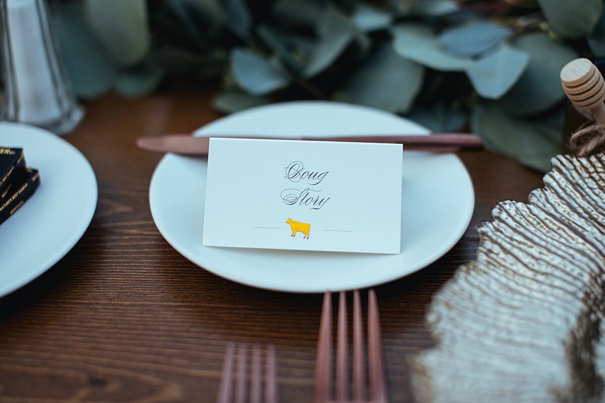 a close up photo of the bread and butter plate at a wedding reception with a seating card and butter knife.
