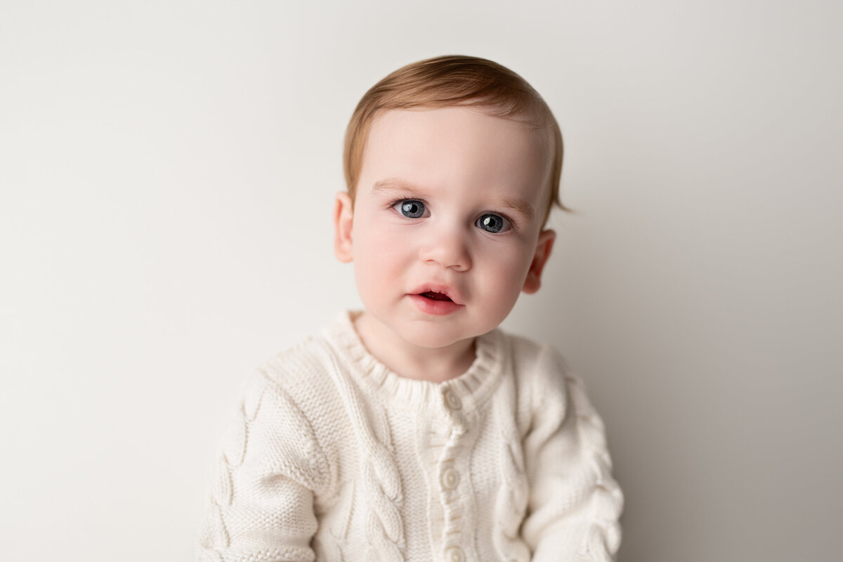 Clean, classic milestone studio portrait of a young boy in soft textures—perfect for timeless keepsakes.