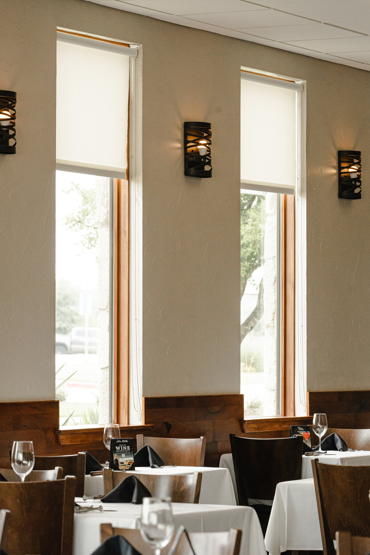 restaurant interior design with wood wainscoting and wall sconces between windows