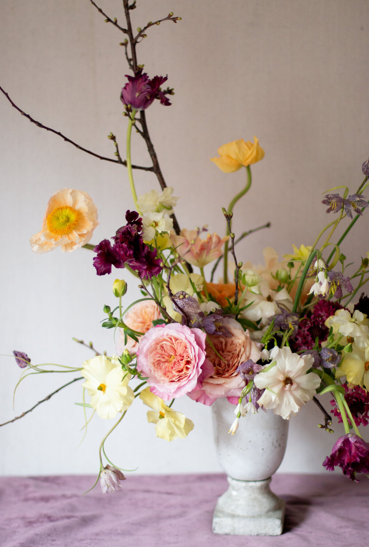 Colourful, lush spring flowers and branches in a floral wedding arrangement.