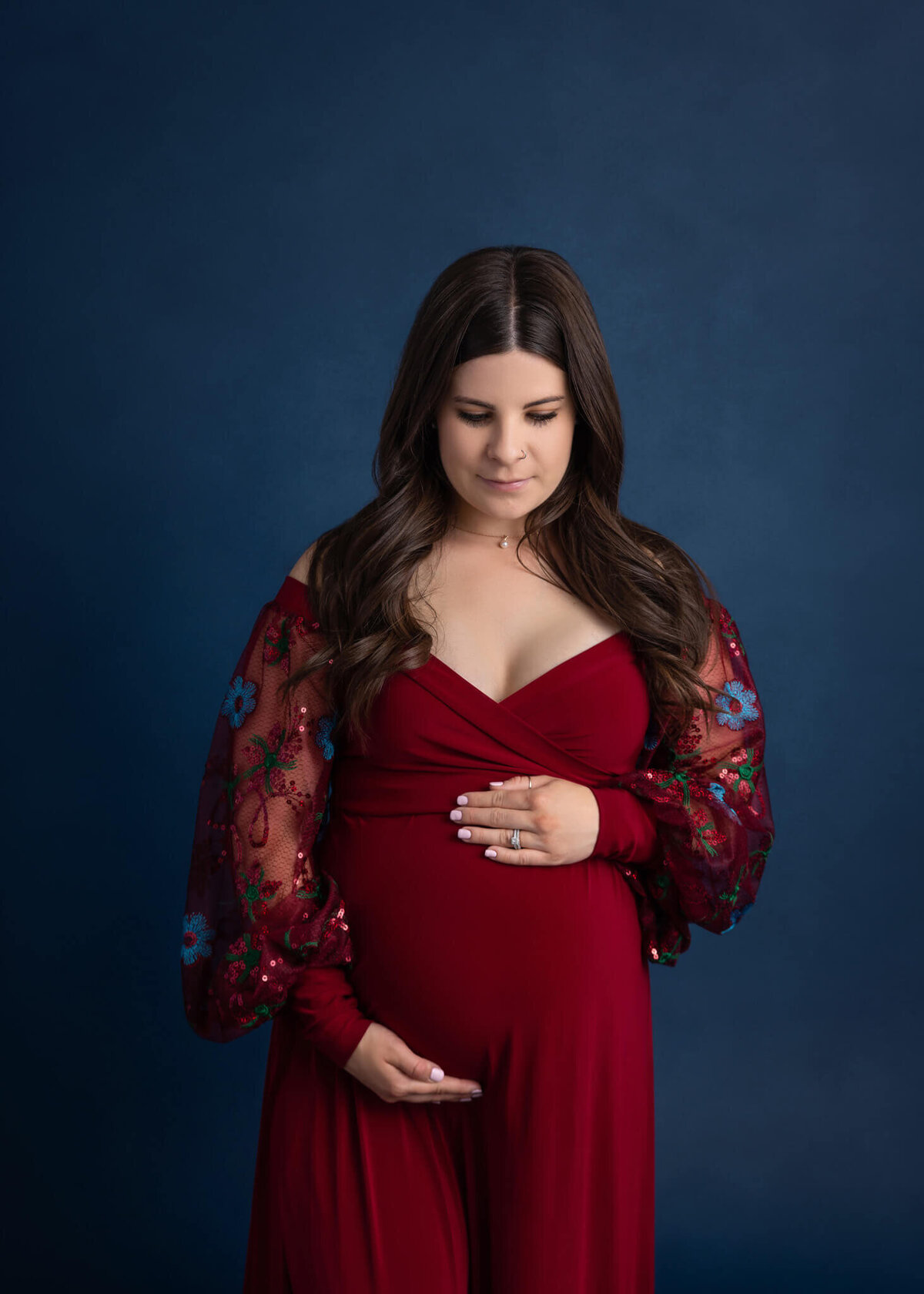 pregnant mom wearing red dress cradling her belly