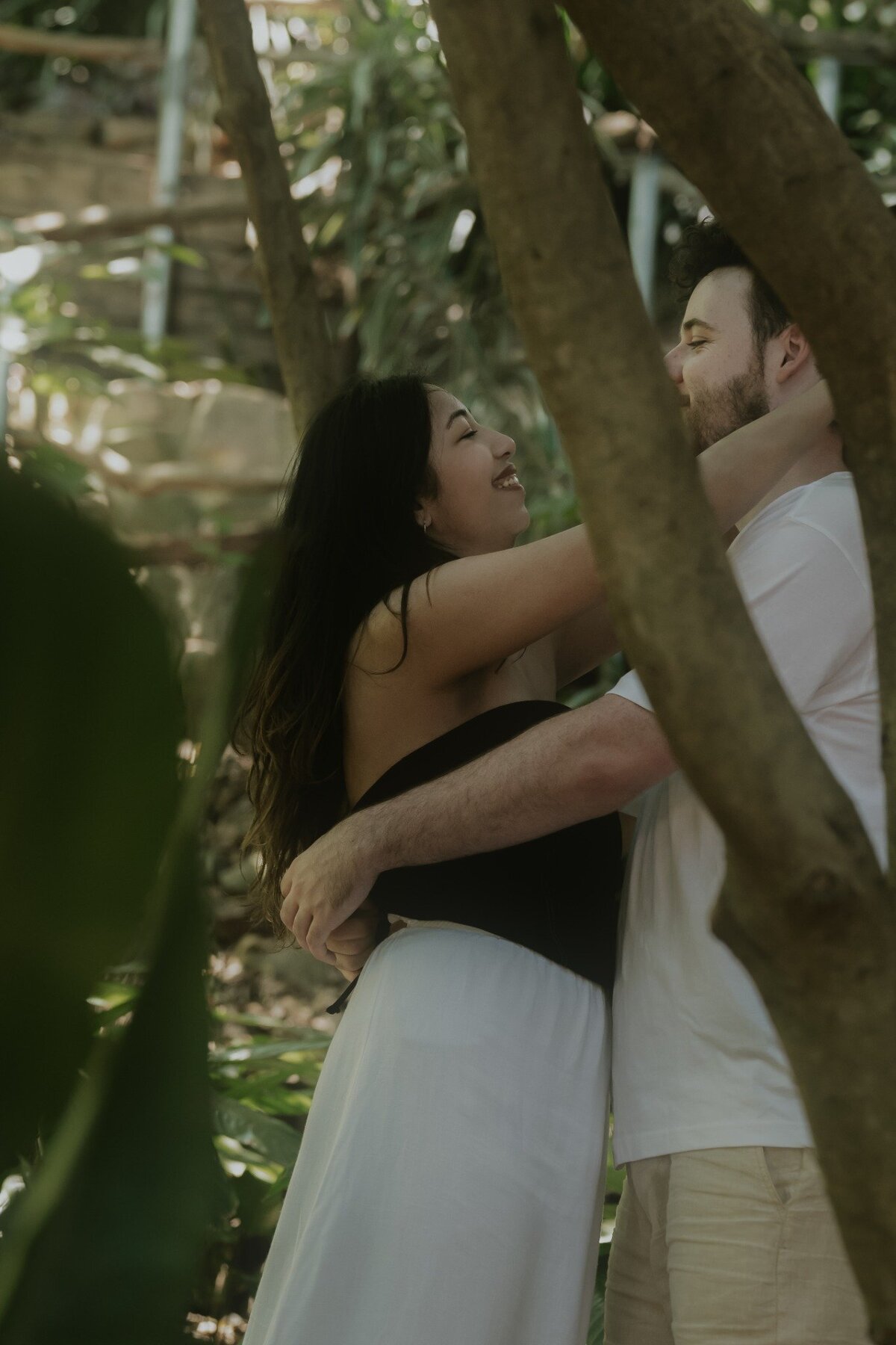 Intimate engagement photo of a couple embracing among the trees at Wendy’s Secret Garden, Sydney.