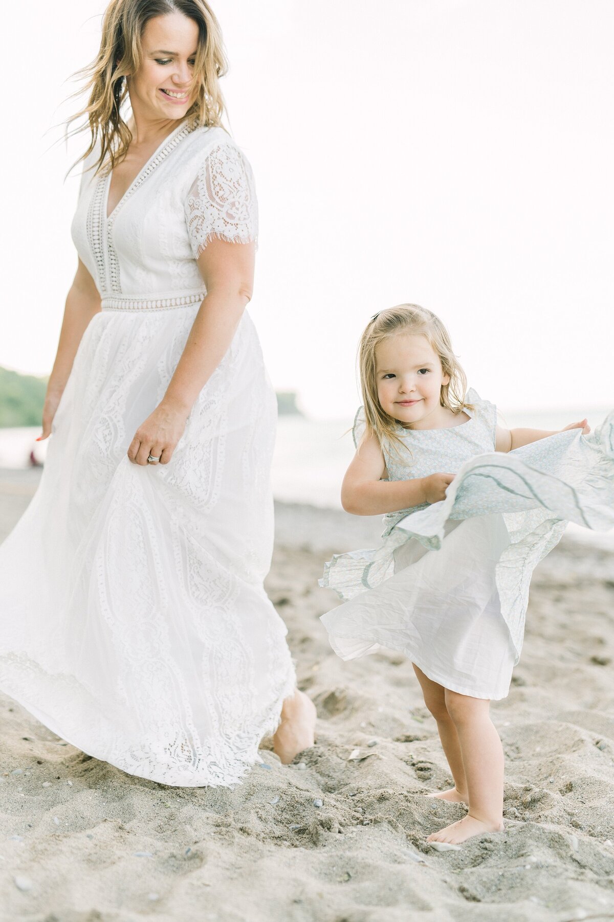 Mom and daughter are dancing on the beach both twirling their dresses