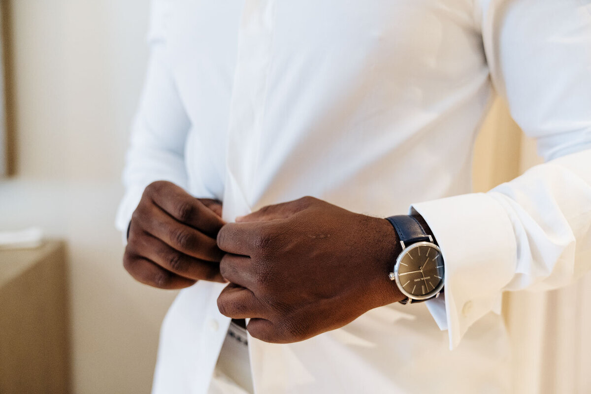 Close-up of groom adjusting his shirt cuffs and wearing a watch