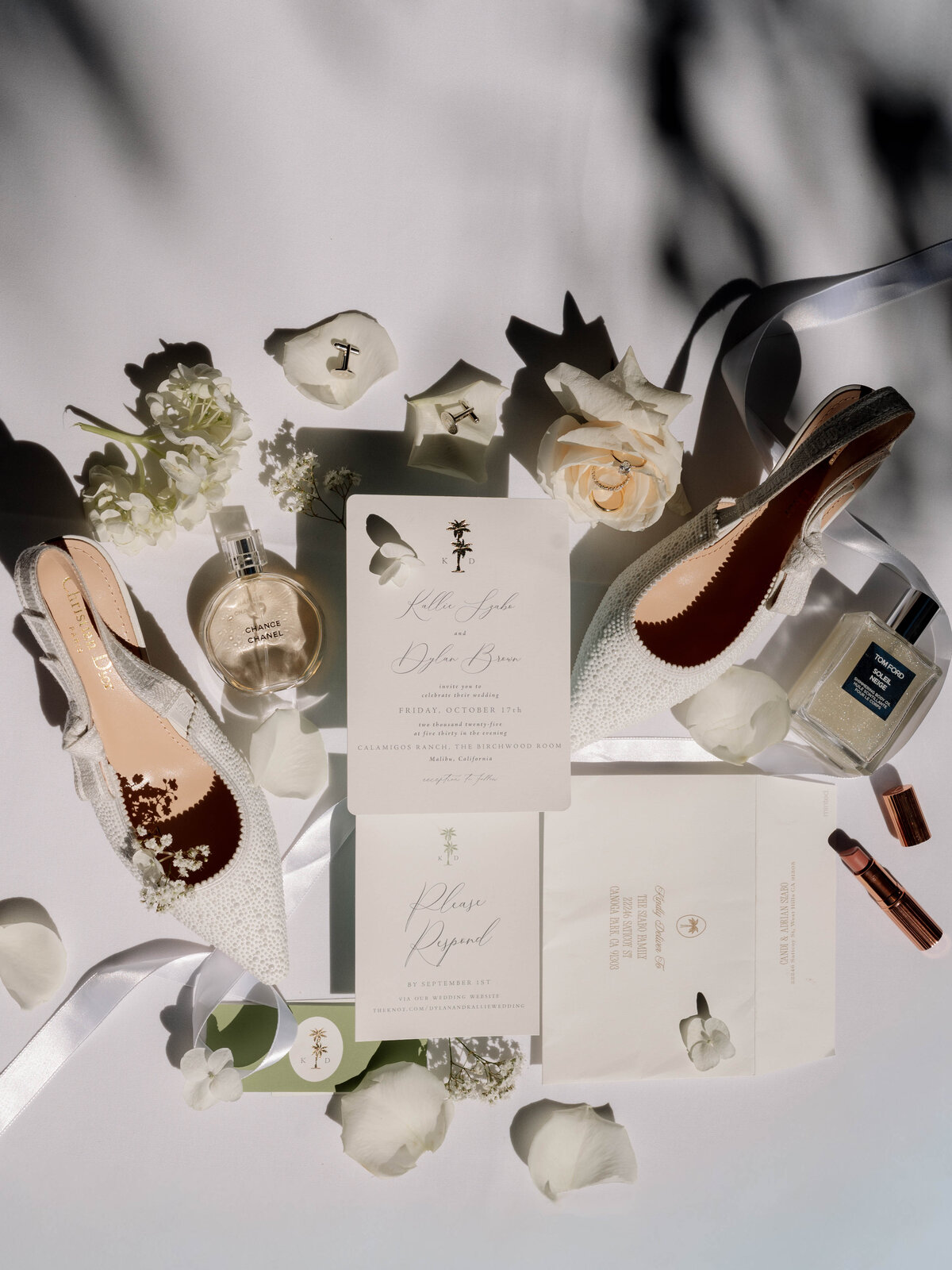A bride and groom lean over a champagne tower, both sipping from green glassware.