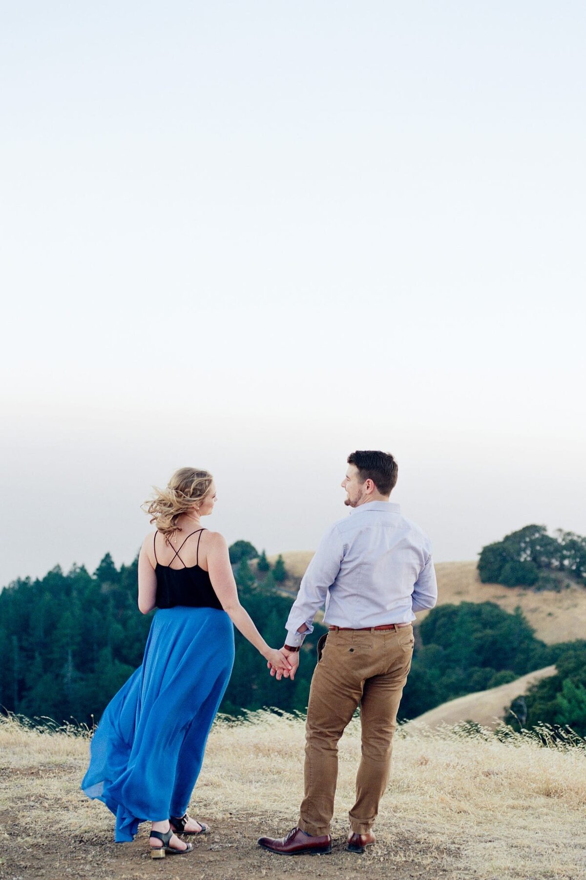 Pretty lady and her fiance hold hands at Mount Tamalpais in California in anticipation of their mountaintop engagement photography by Robin Jolin.