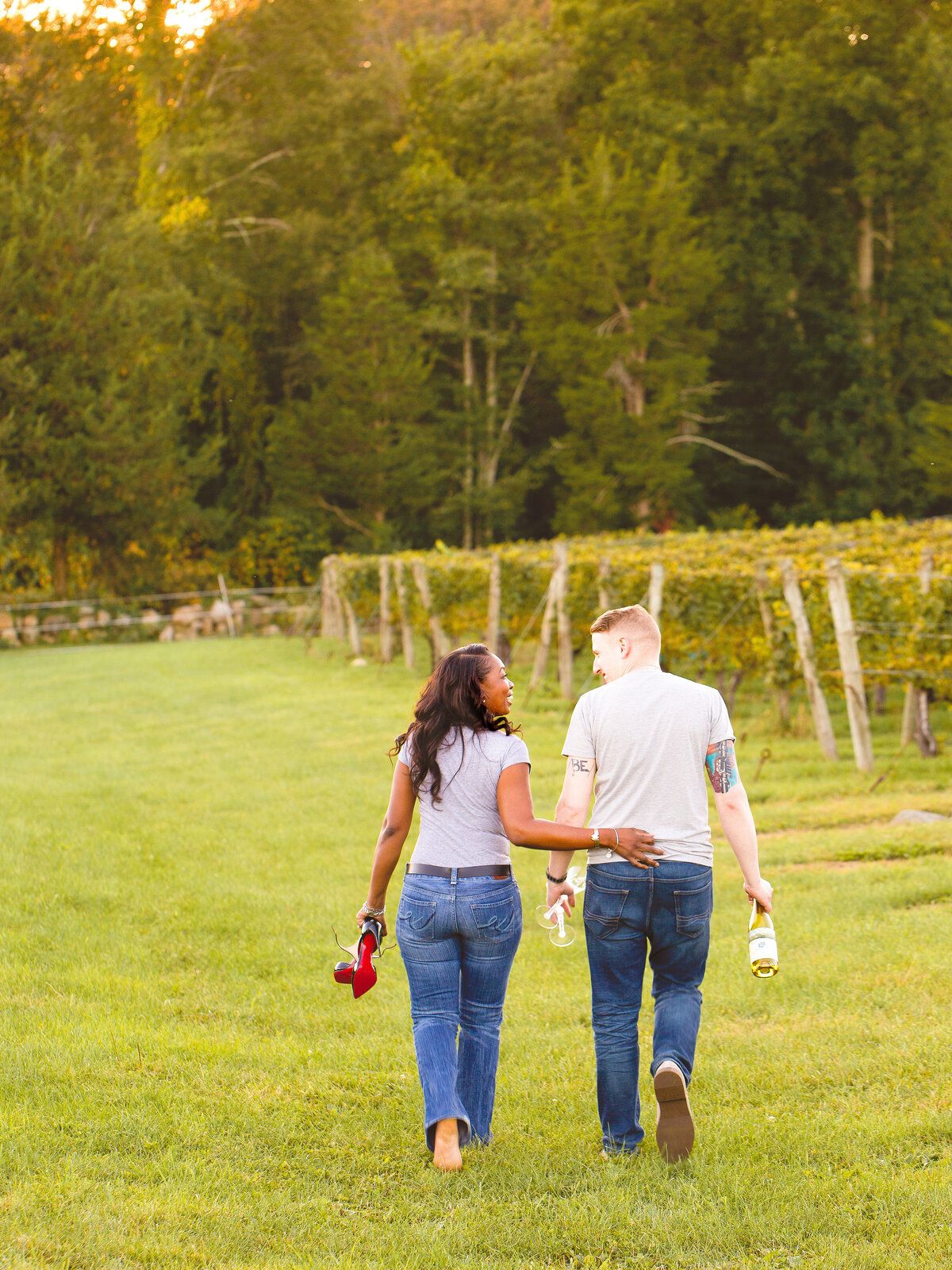 Woman walks barefoot through a vineyard with her fiancé.