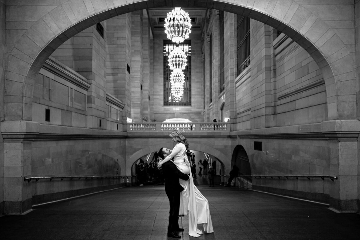 Groom holding his bride up inside of Grand Central Station.