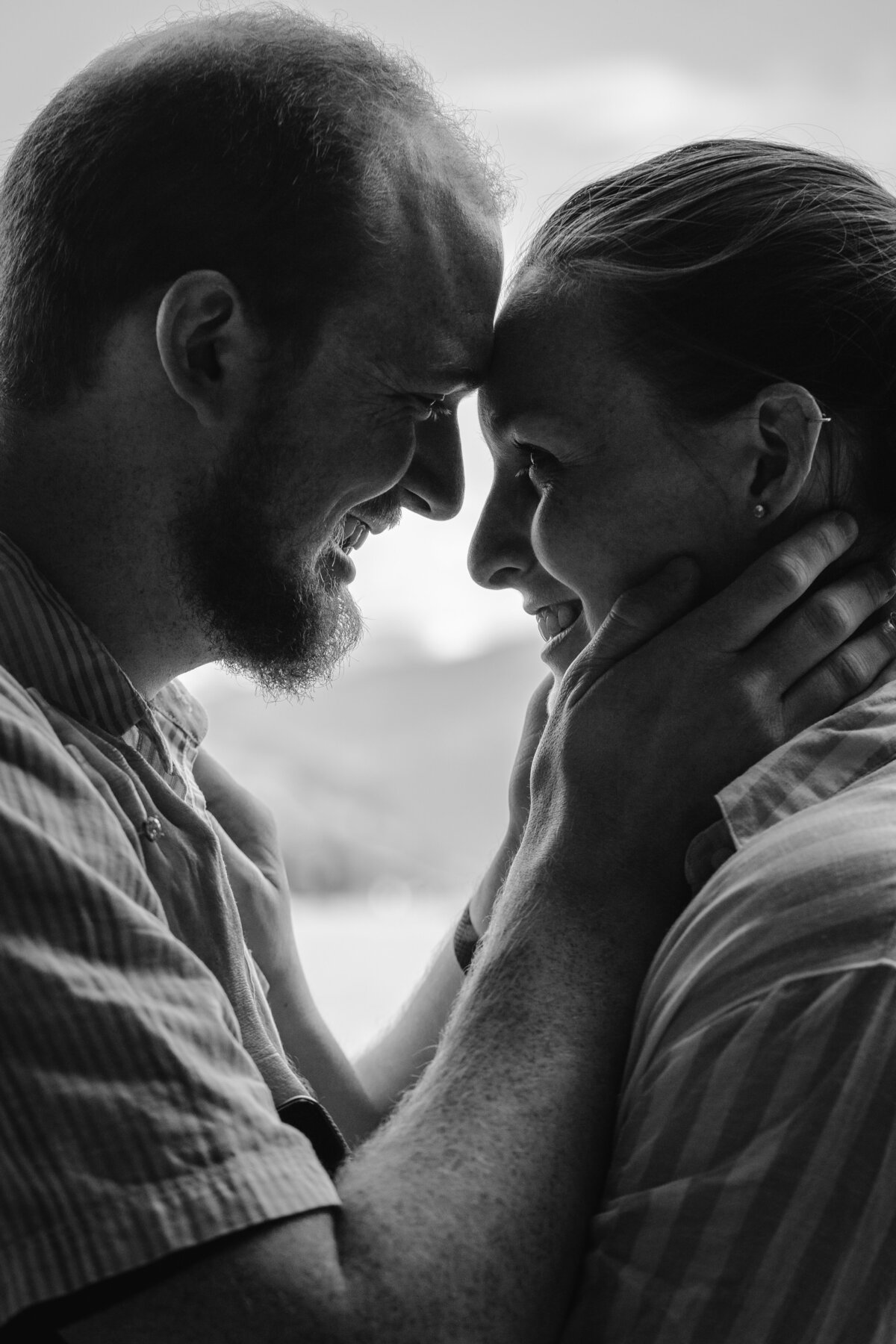 A couple standing forehead to forehead smiling