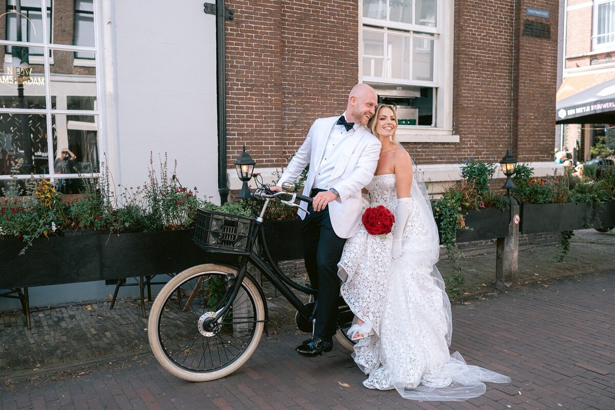 Trouwfotograaf Amsterdam maakt foto terwijl bruidspaar op de fiets zit