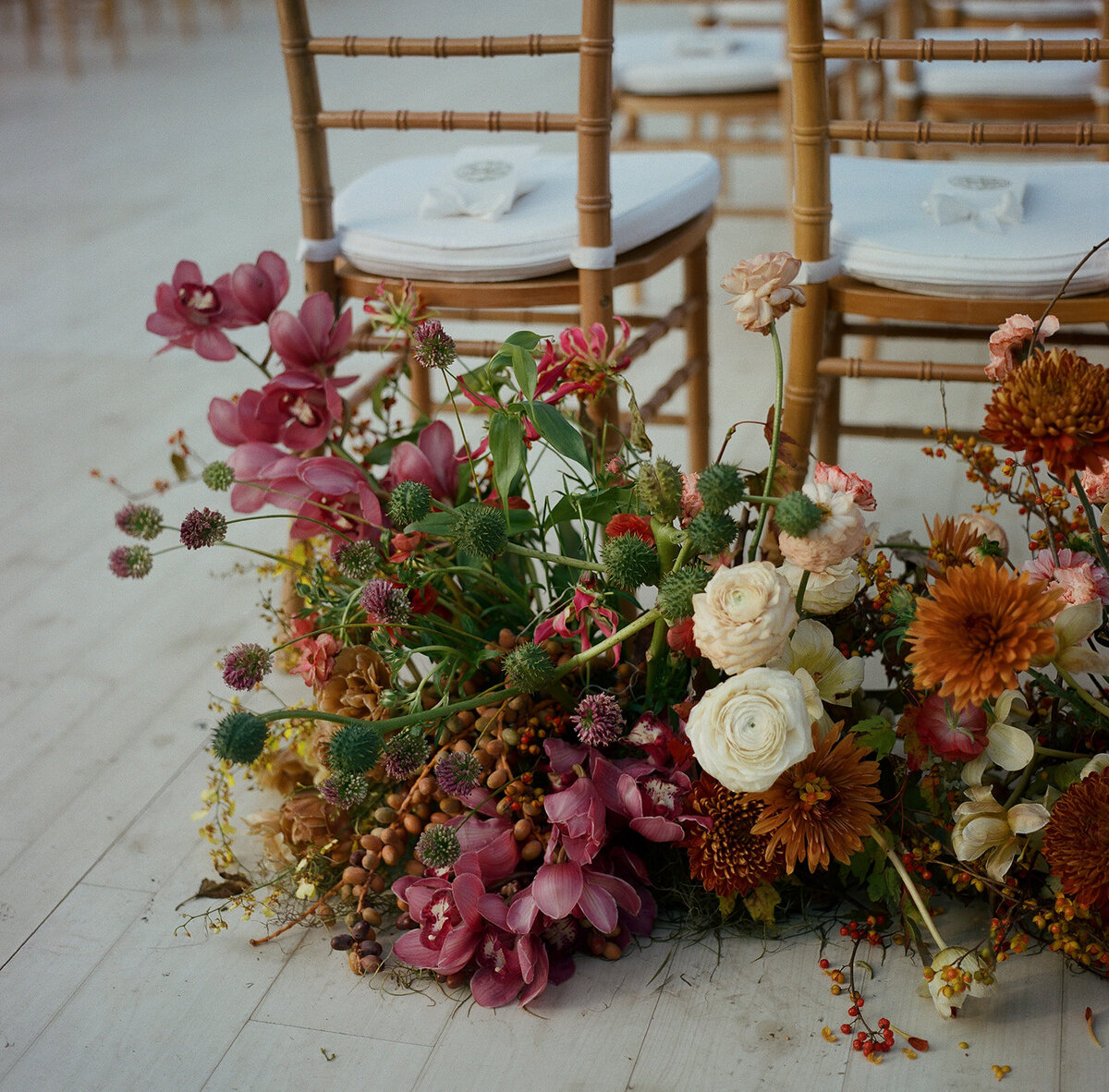 Product clustered floral meadows for entrance to wedding ceremony aisle. Unique fall wedding colors in copper, ruby, lavender, and gold. Artistic and sculptural floral design for fall wedding in Tennessee hills. Flowers featuring ranunculus, orchids, tulips, and dahlias. Custom build platform for private property wedding ceremony. Private home wedding ceremony and reception. Design by Rosemary & Finch Floral Design in Nashville, TN.