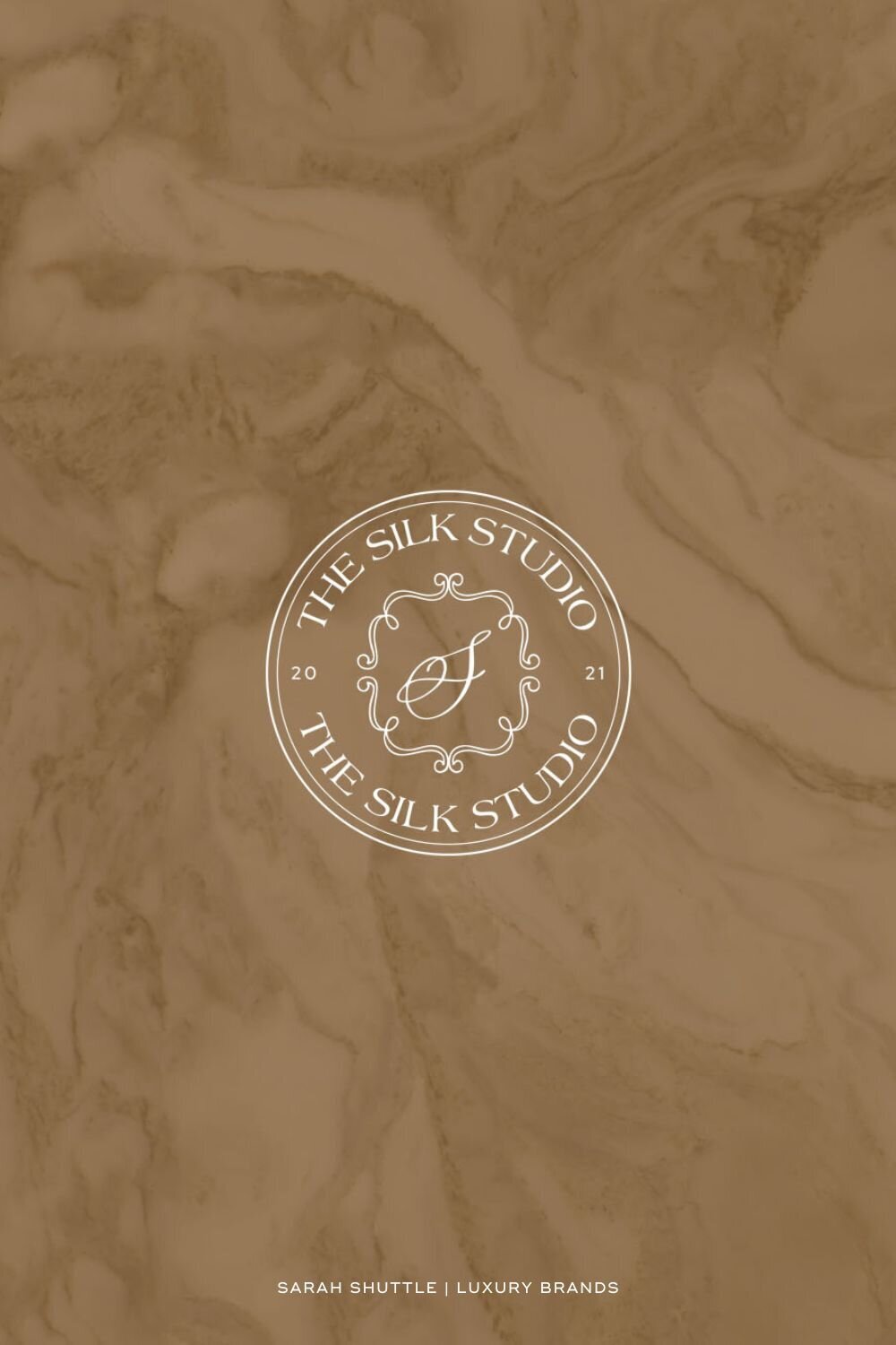 Refined brand submark for The Silk Studio placed on warm tan marble background