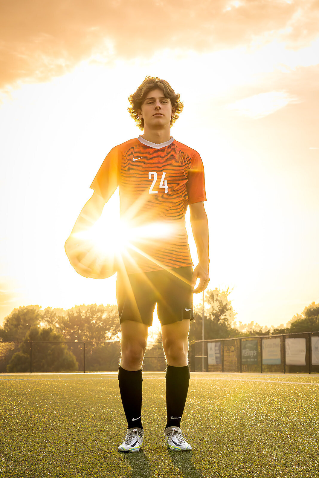 senior with soccer ball and sunburst on soccer field