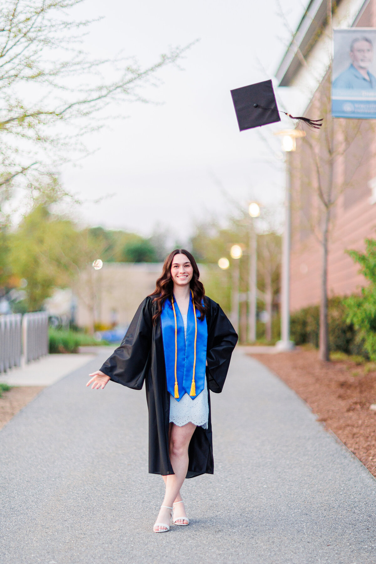 A girl throwing her mortarboard in the air representing Boston senior cap and gown photography