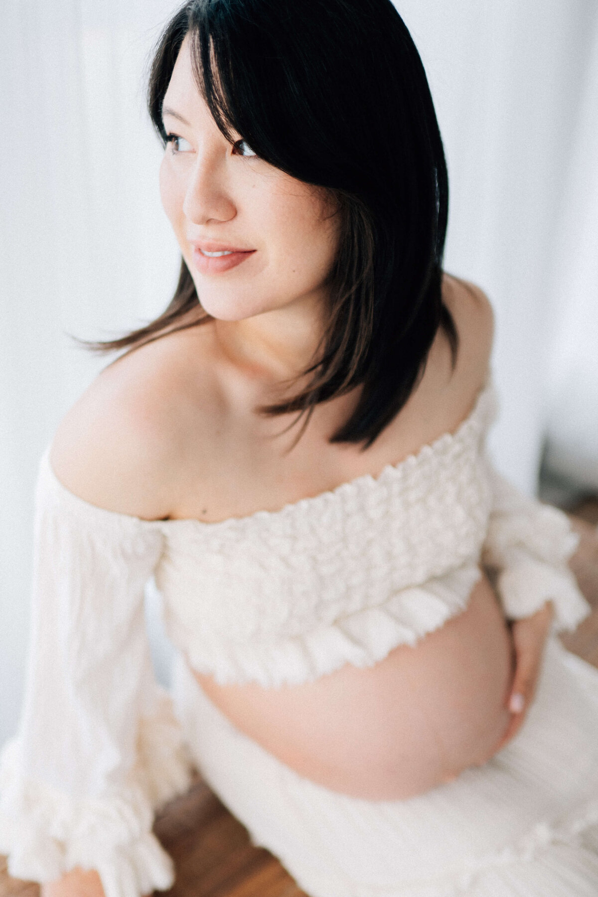 pregnant woman holding her belly while looking out the window