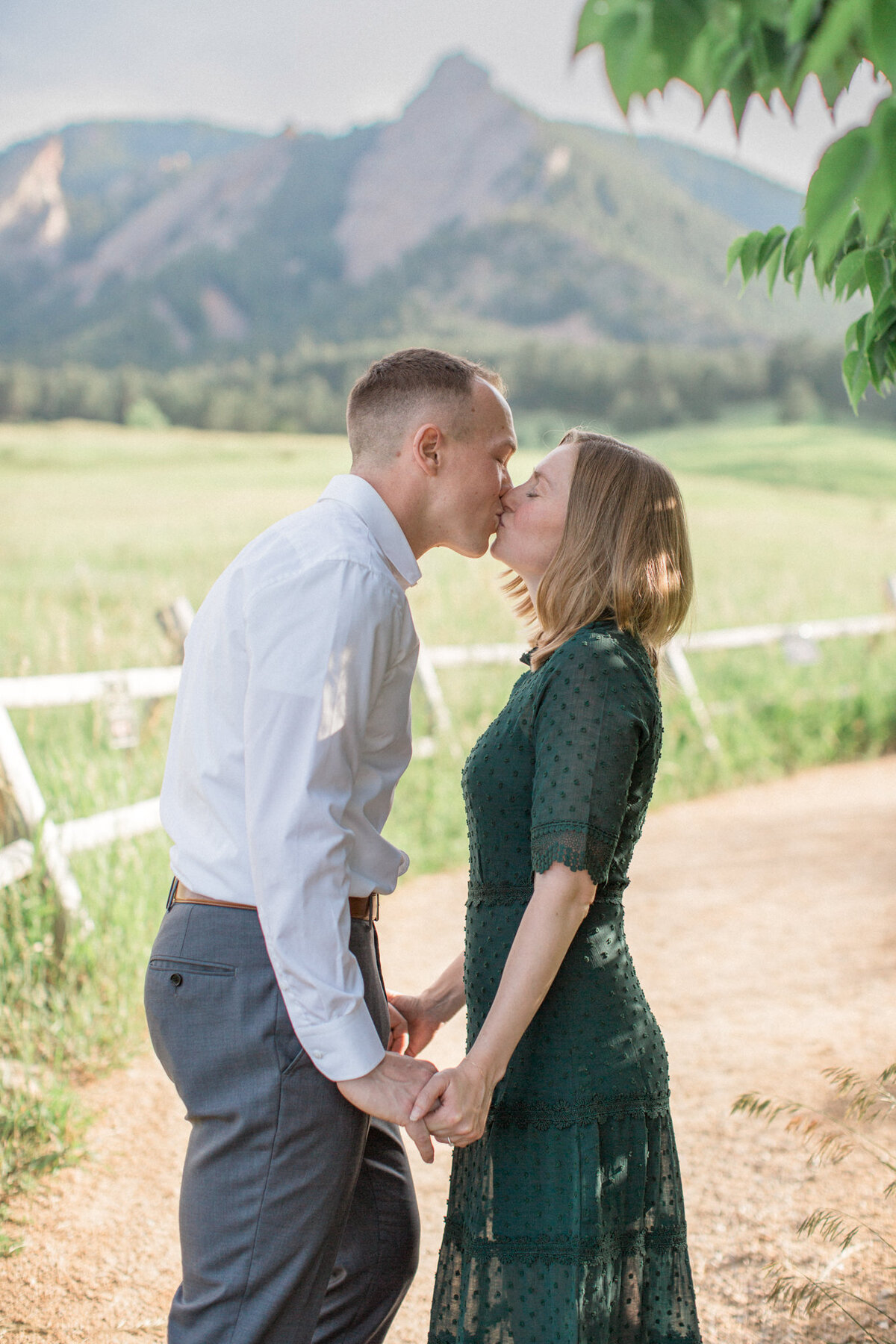 An engaged couple kiss in front of the Flatirons in Boulder, Colorado