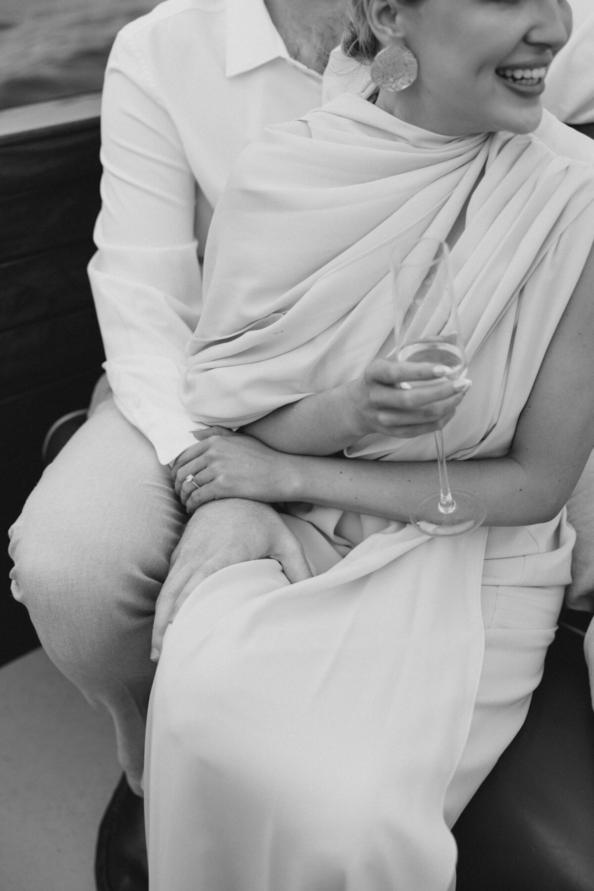 Girl holds champagne glass while cuddling guy on lake oconee boat engagement session