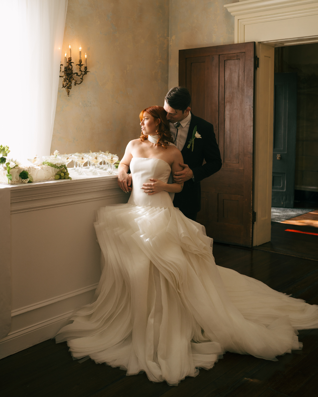 A bride and groom standing at a bar holding each other at Riverwood Mansion, a Nashville Wedding venue. 