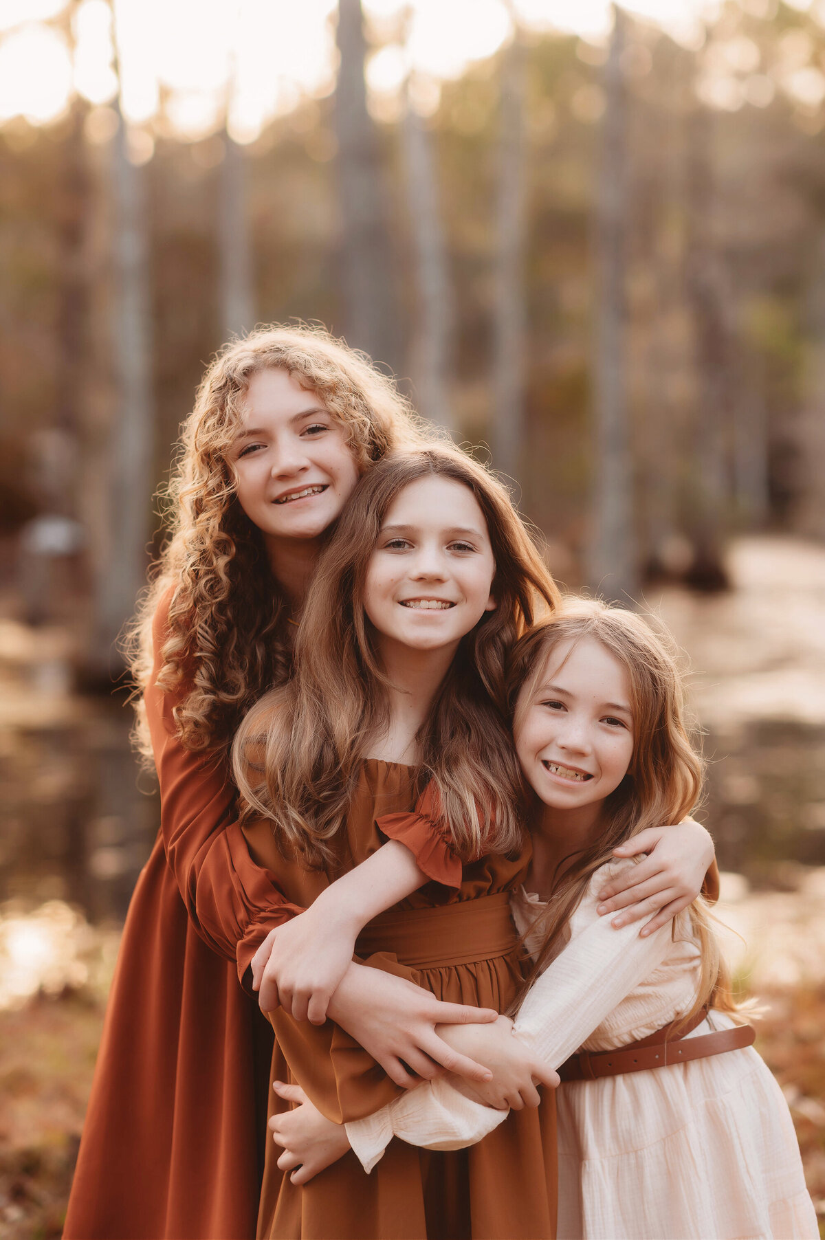Sisters embrace each other Little girl smiles at the camera during  Family Portraits at Cypress Gardens near Charleston, South Carolina.
