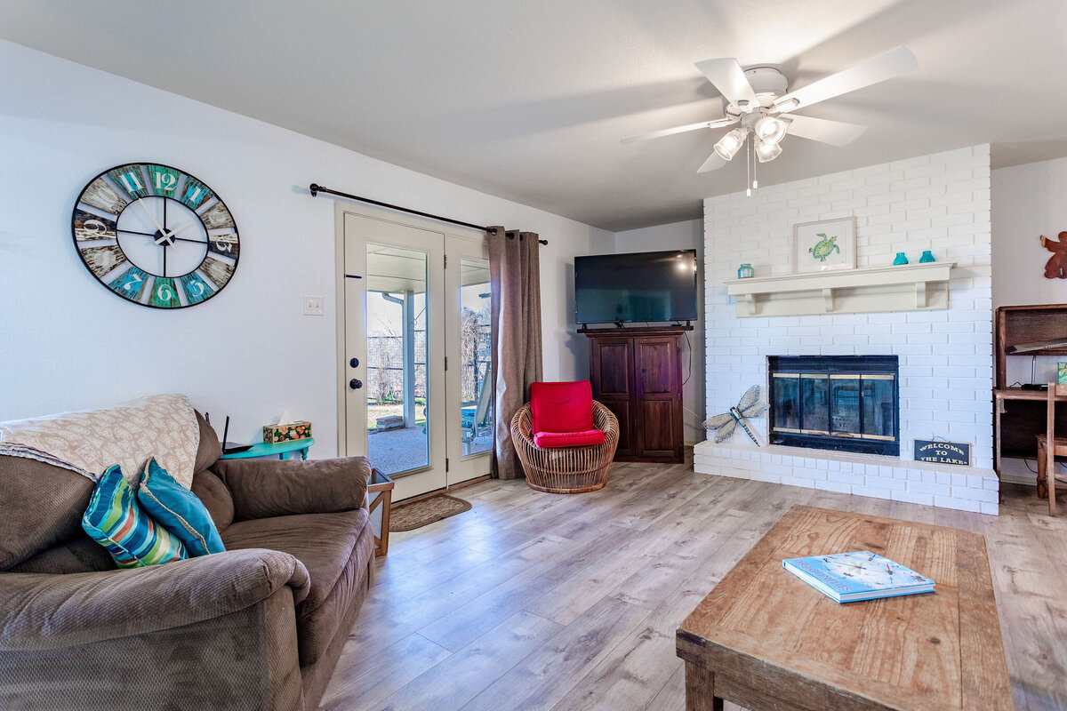 Living room with plenty of seating and smart TV in this 2-bedroom, 2-bathroom lakeside vacation rental home for 6 guests on Tradinghouse Lake with privacy access to a fishing dock and boat launch pad, ping pong table, gazebo, free wifi and free parking in Waco, TX.