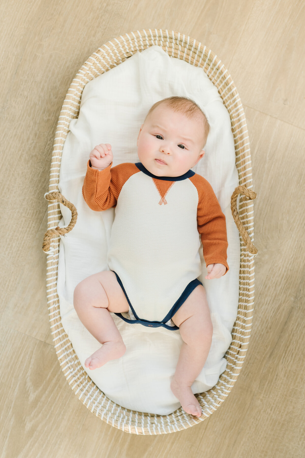 Baby in orange and white onesie in basket - Washington DC Newborn Photographer