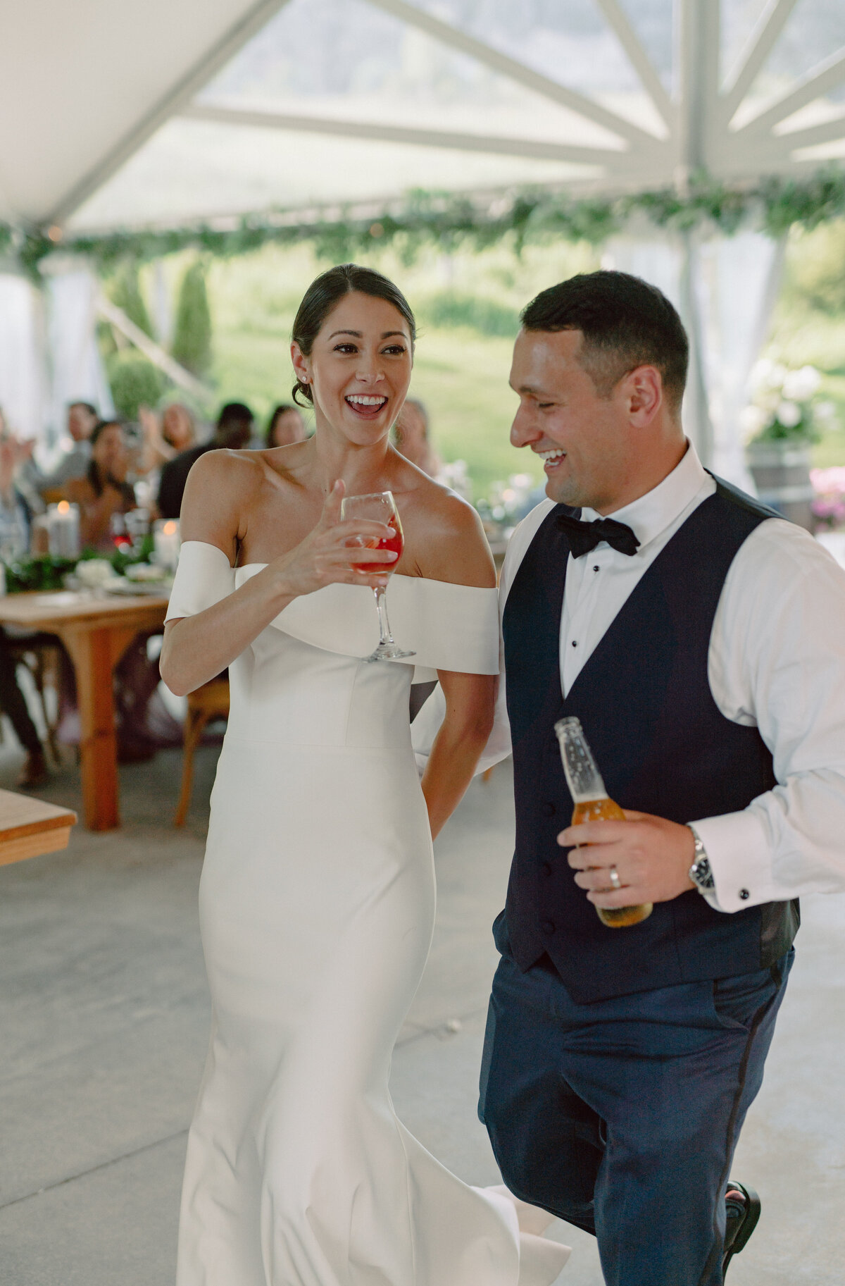 Bride and Groom holding Fingerlakes Wine being introduced under the tent recep;tion at Crispin Hill on Keuka Lake, Fingerlakes, NY