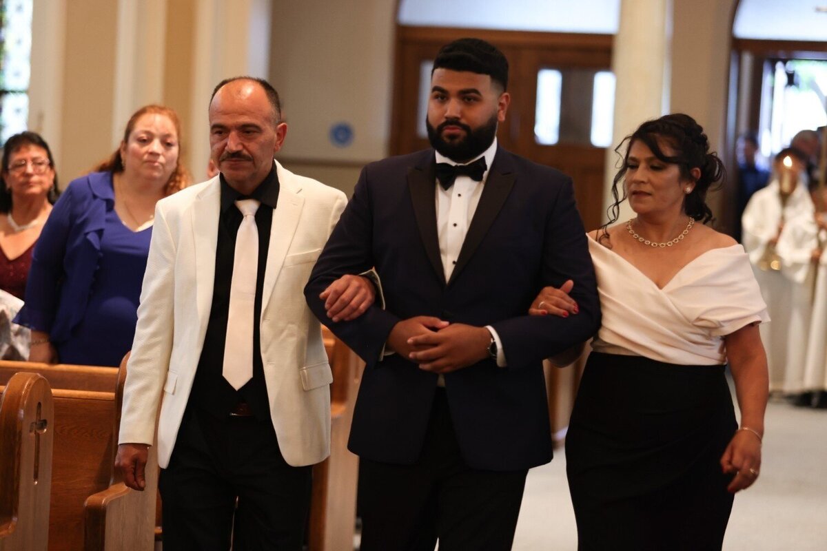 Groom walks down the aisle escorted by both parents at the Union Club Hotel wedding.