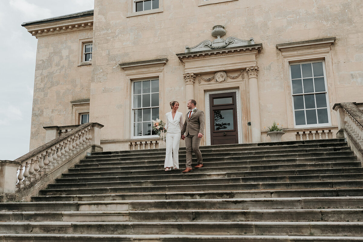 Smiling Bride and Groom walk hand in hand down the steps at Danson House, Bexleyheath