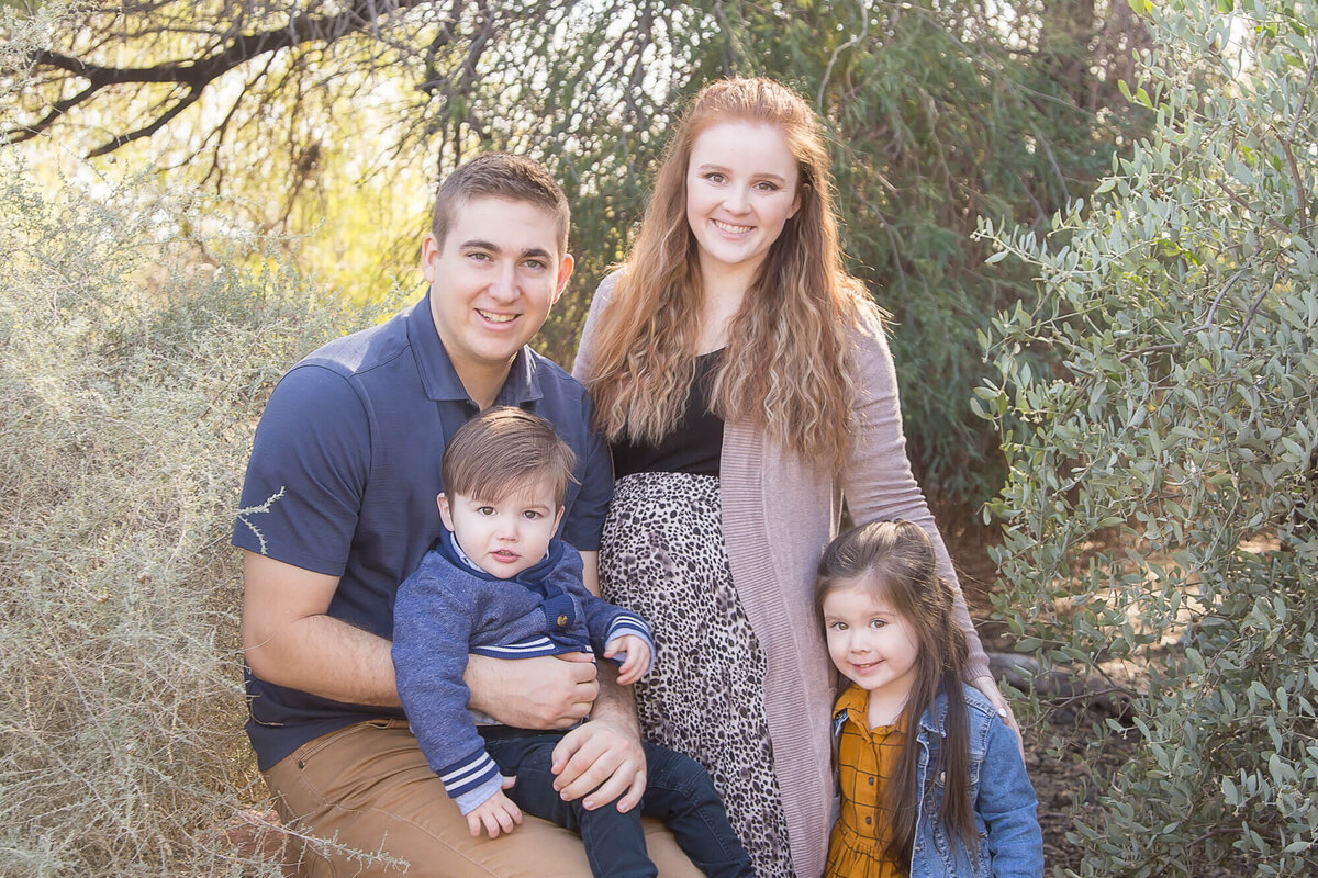 Couple with two kids in blue and brown smiling in a desert park