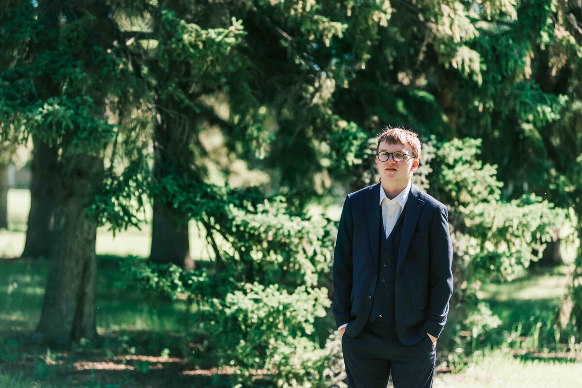 A young man in front of the trees. 