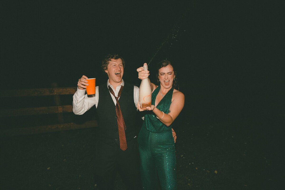 Wedding couple spraying champagne at night at Diamond in the Rough wedding venue near Calgary