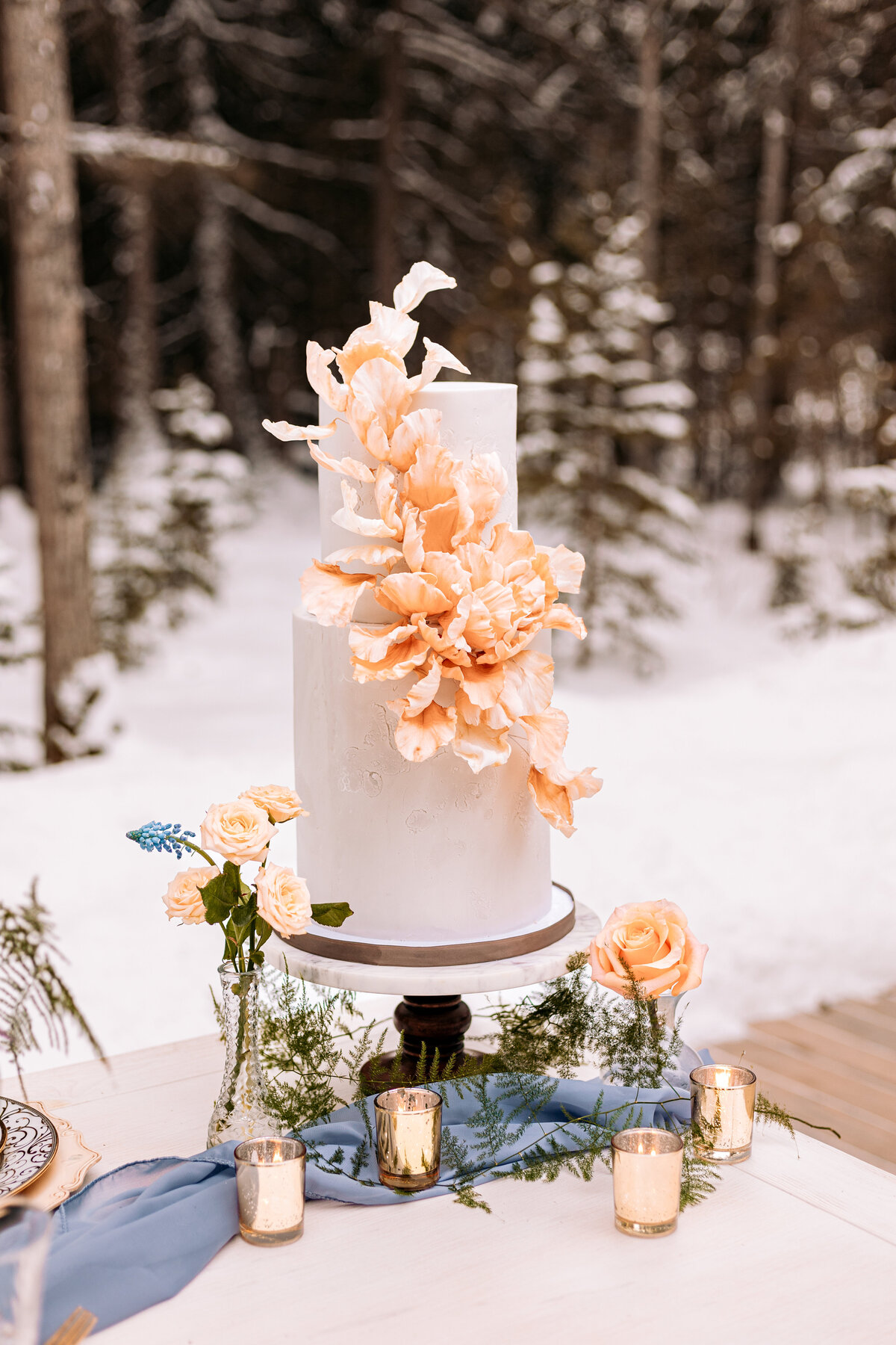 Wedding cake with peach floral accents during a winter wedding