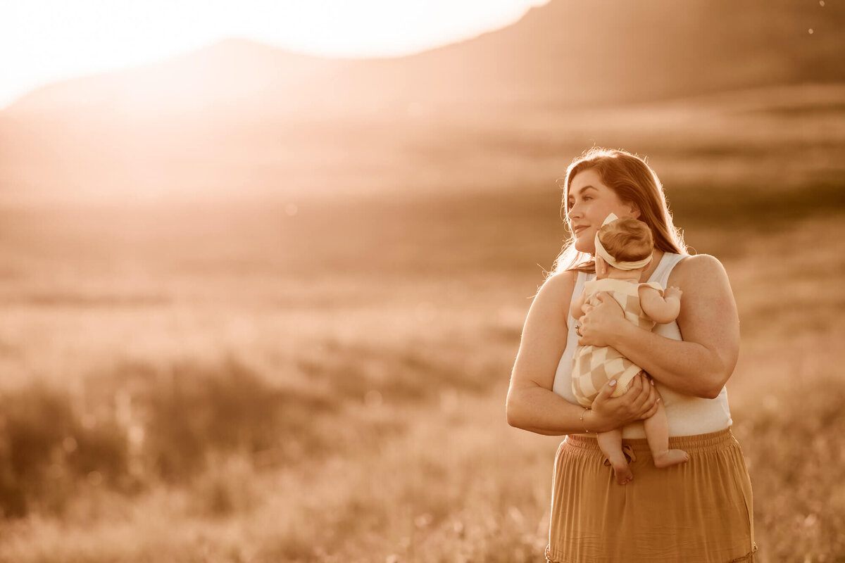Mother holds her baby girl in a field in the Wichita Mountains in Oklahoma.