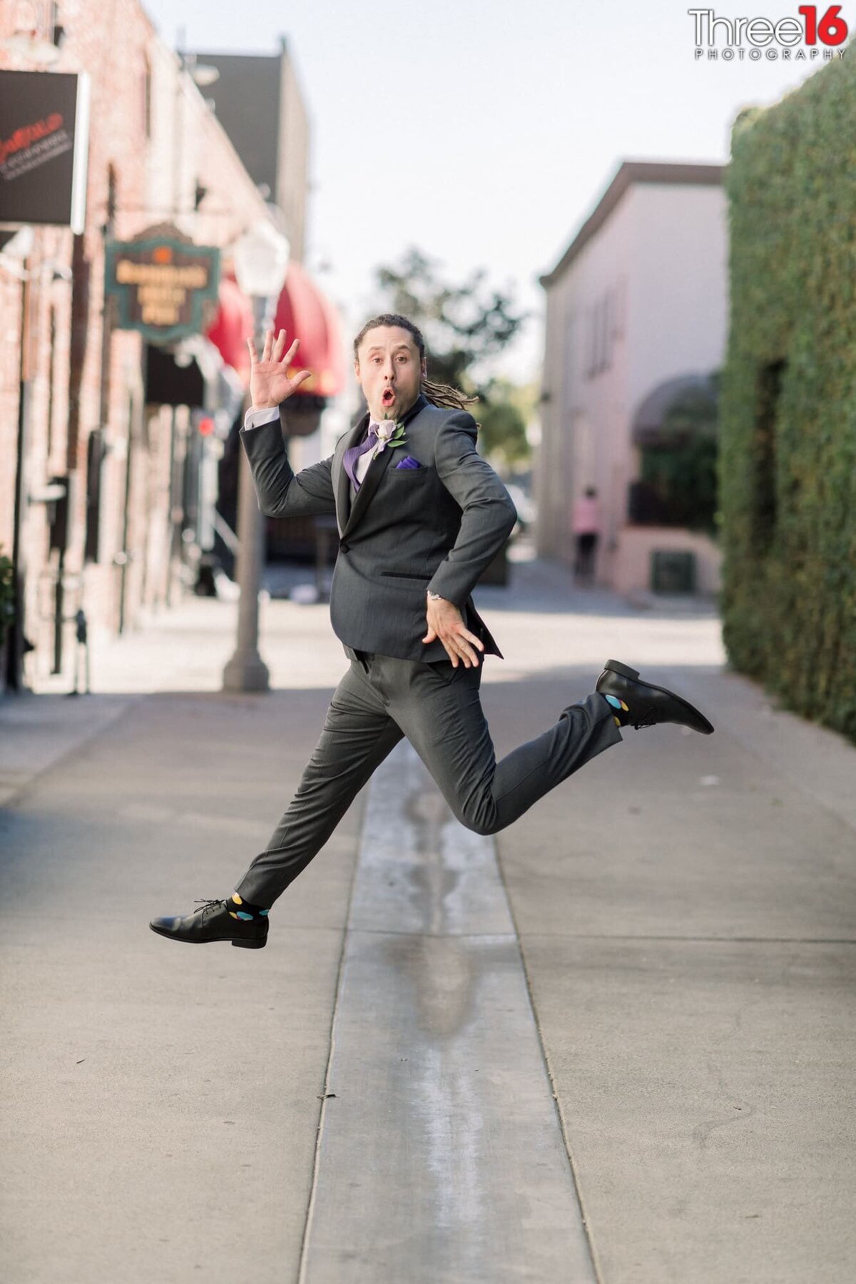 Groom acts goofy as he jumps in the air in mid-stride