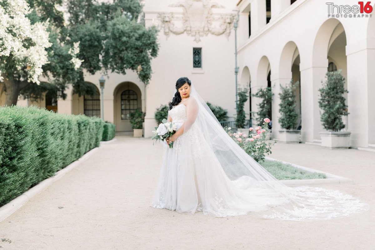 Bride poses with her dress train fanned out while holding her bouquet